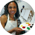 Artist holding a paint palette and brush, smiling in a bright studio