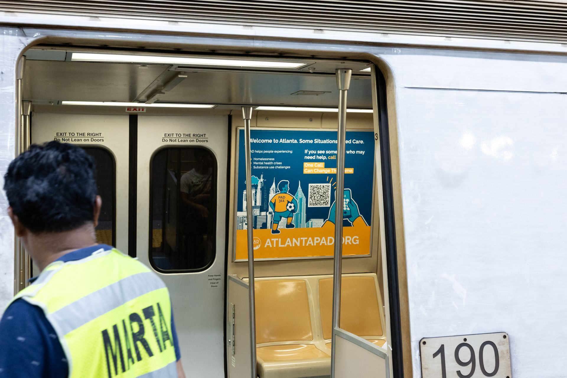 MARTA worker stands at an open train door beside a white train car with route sign 190.