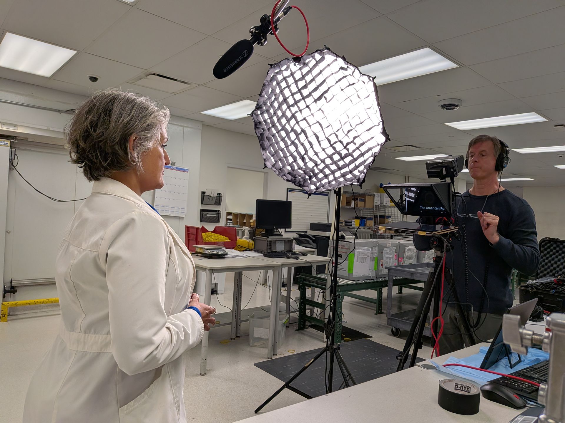 Two people in a studio with a large softbox light and camera equipment.