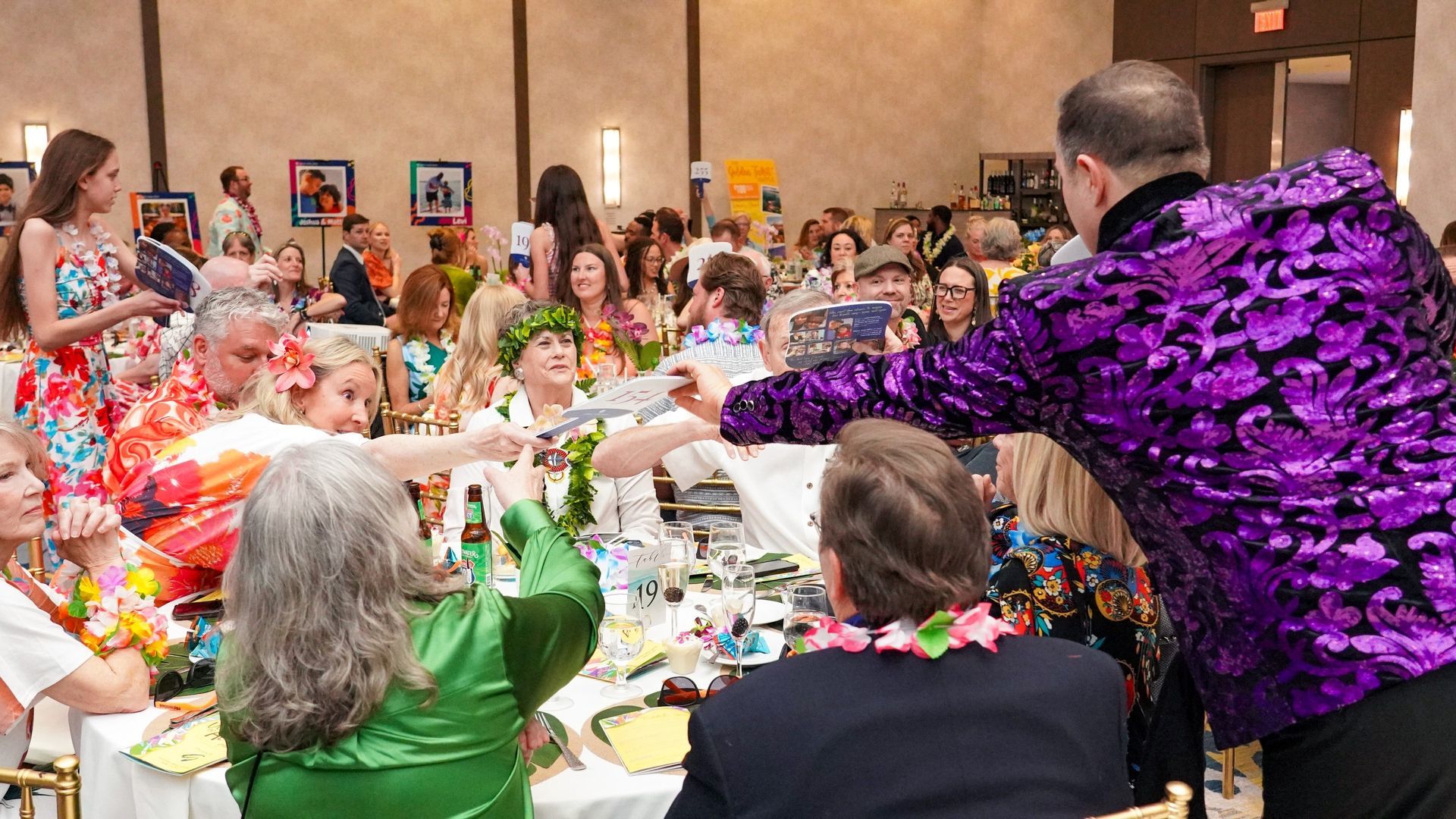 Costumed guests seated at decorated banquet tables, raising glasses in a lively party hall