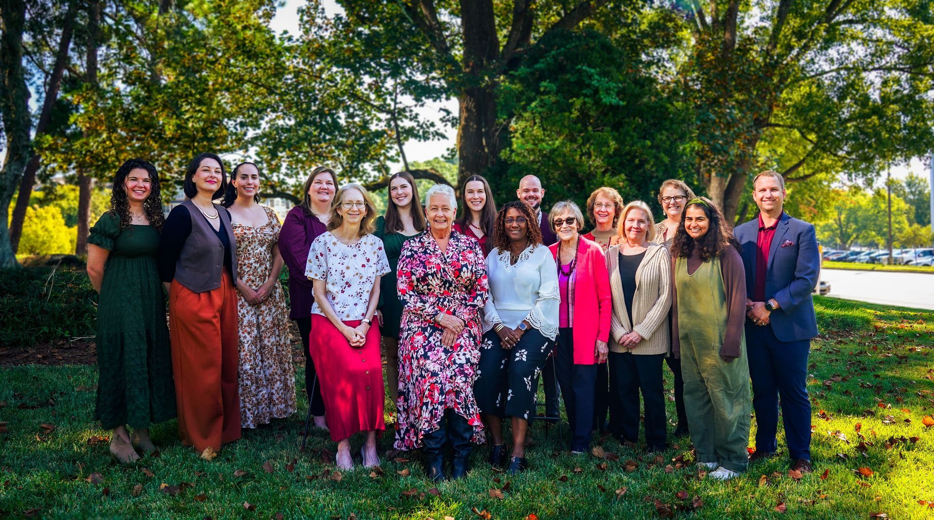 Group of people posing outdoors in formal attire in a green park setting