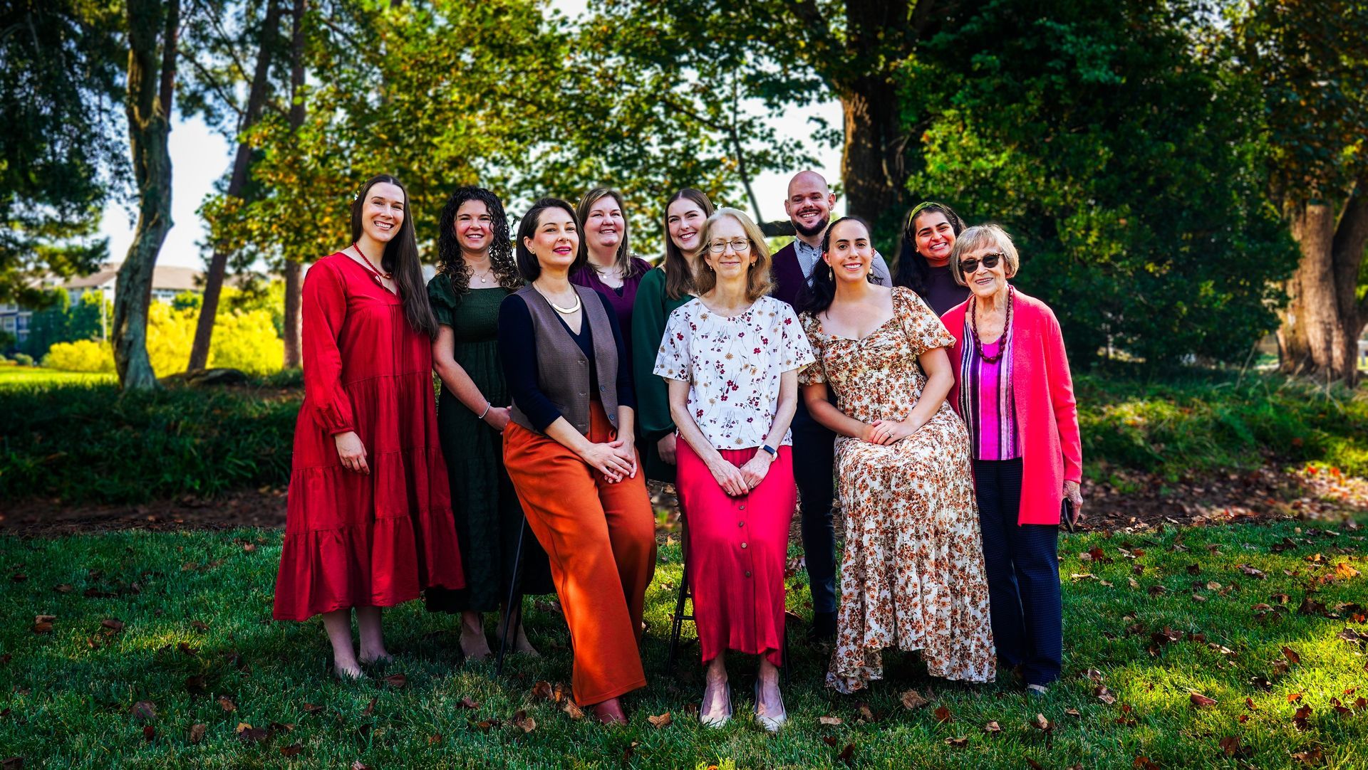 Group of people standing outdoors in a park, dressed in colorful clothes, posing for a photo.
