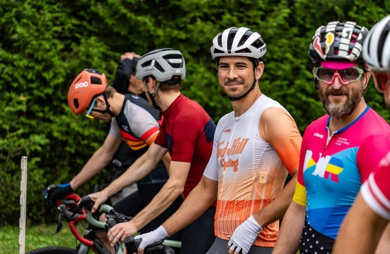 Four cyclists in helmets and jerseys lined up outdoors on a scenic road