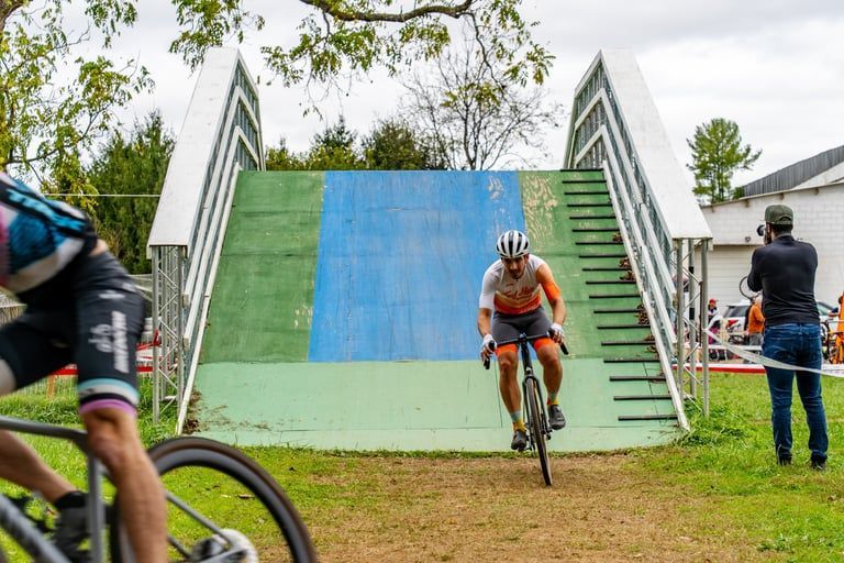 Cyclist racing down a blue-and-green ramp at an outdoor bike course