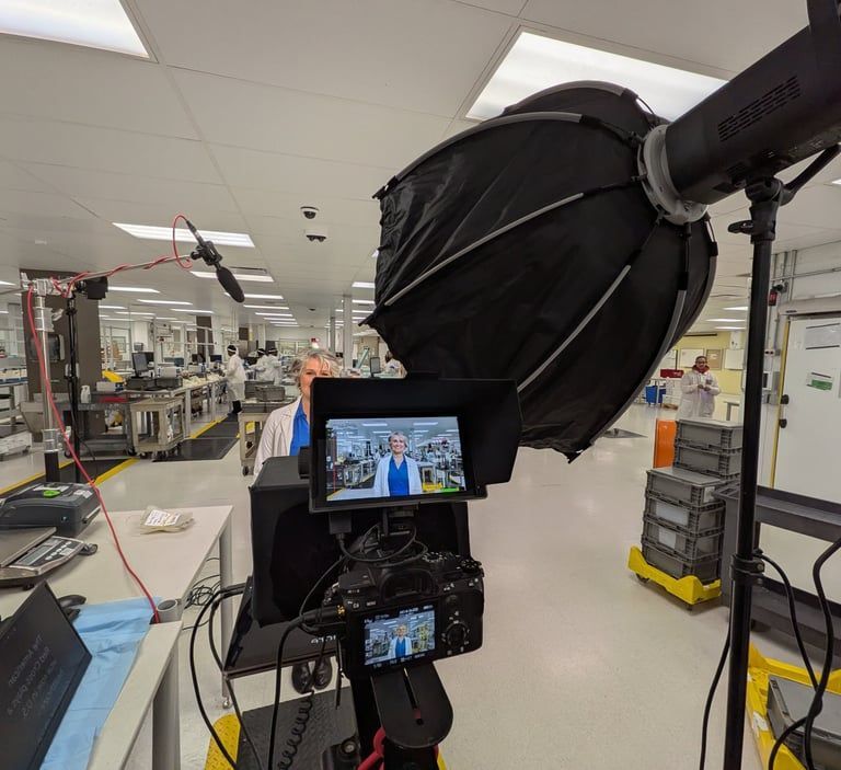 Camera and monitor setup in a bright industrial lab, with a large black light diffuser in the foreground.
