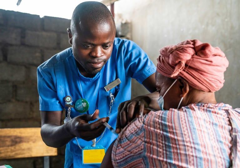 Health worker in blue shirt checks a patient’s arm in a clinic setting