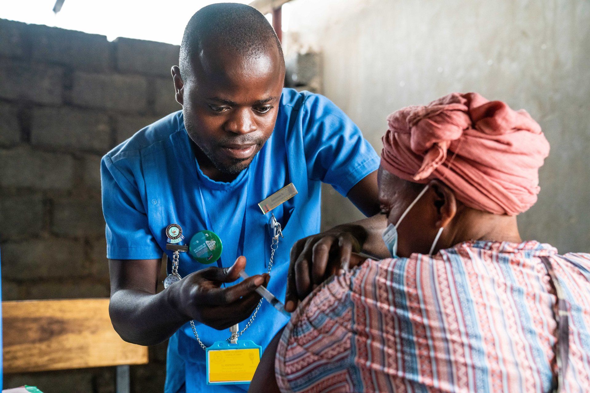 Healthcare worker showing a device to a seated patient in a clinic