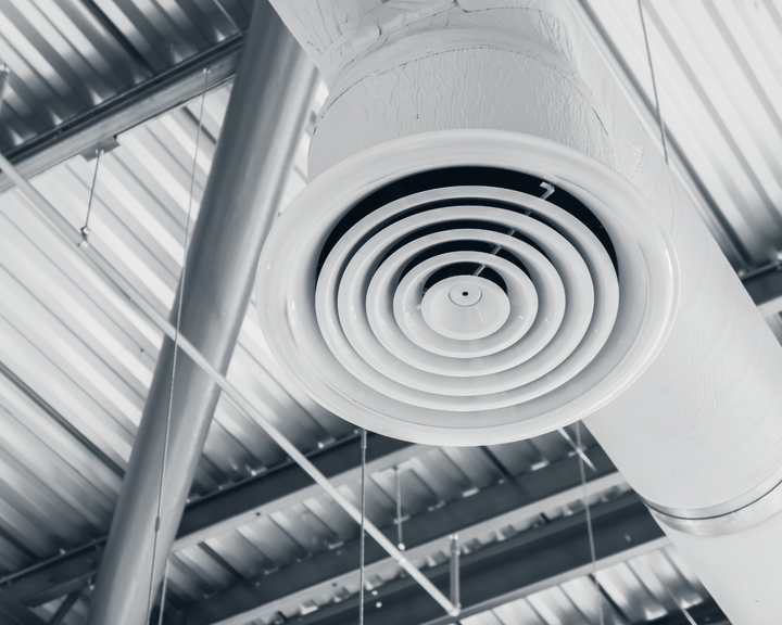 A white air vent is hanging from the ceiling of a building.