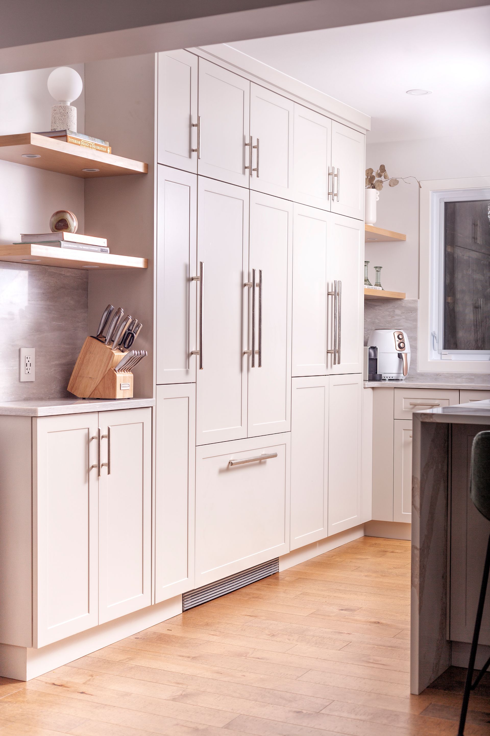 a kitchen with white cabinets , a refrigerator , and a cutting board .