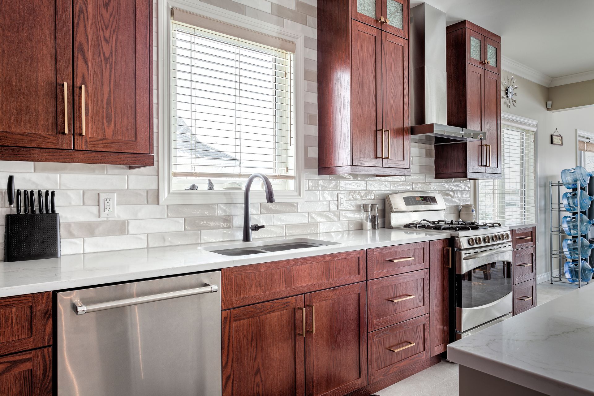 Modern kitchen featuring warm-toned wood cabinets, stainless steel appliances, light countertops, and subway tile backsplash.