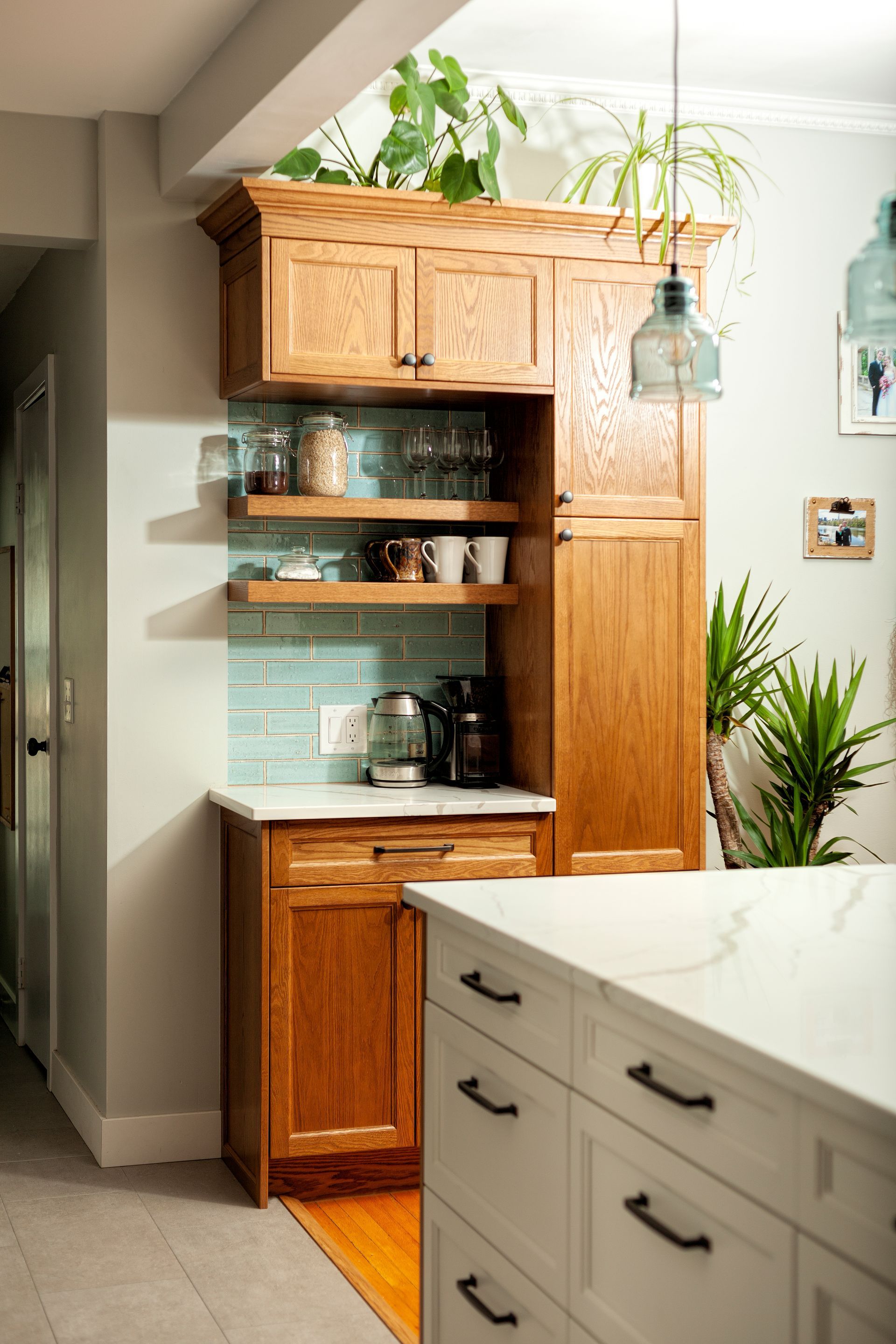 A kitchen corner featuring wooden cabinets, light blue subway tile, open shelving, and white countertops.