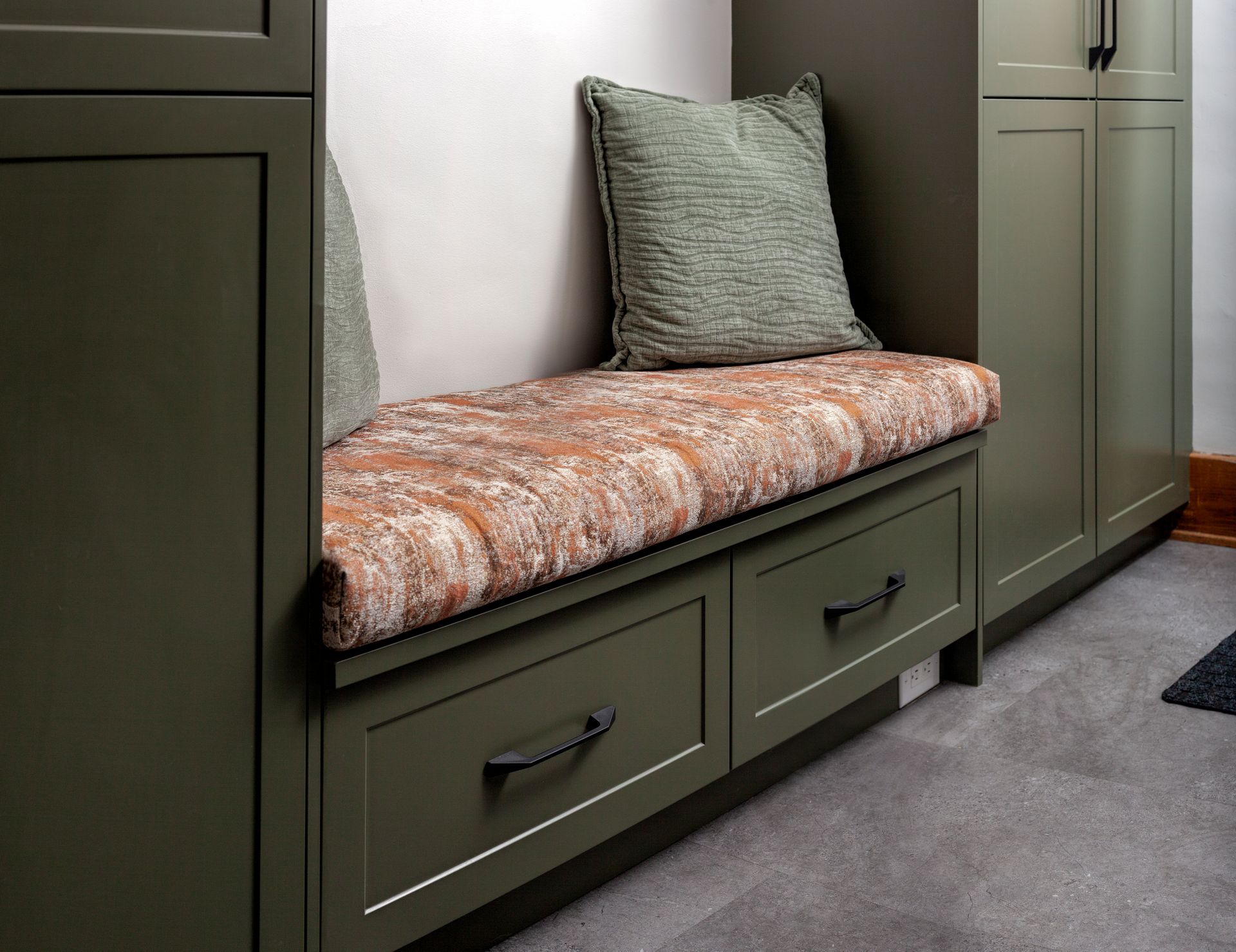 A bench with drawers underneath it and a pillow on it.
