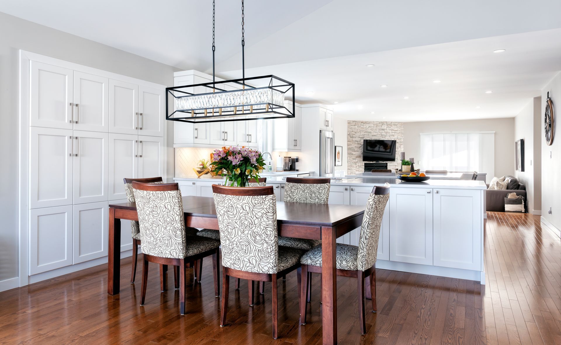 a dining room table and chairs in a kitchen with white cabinets .