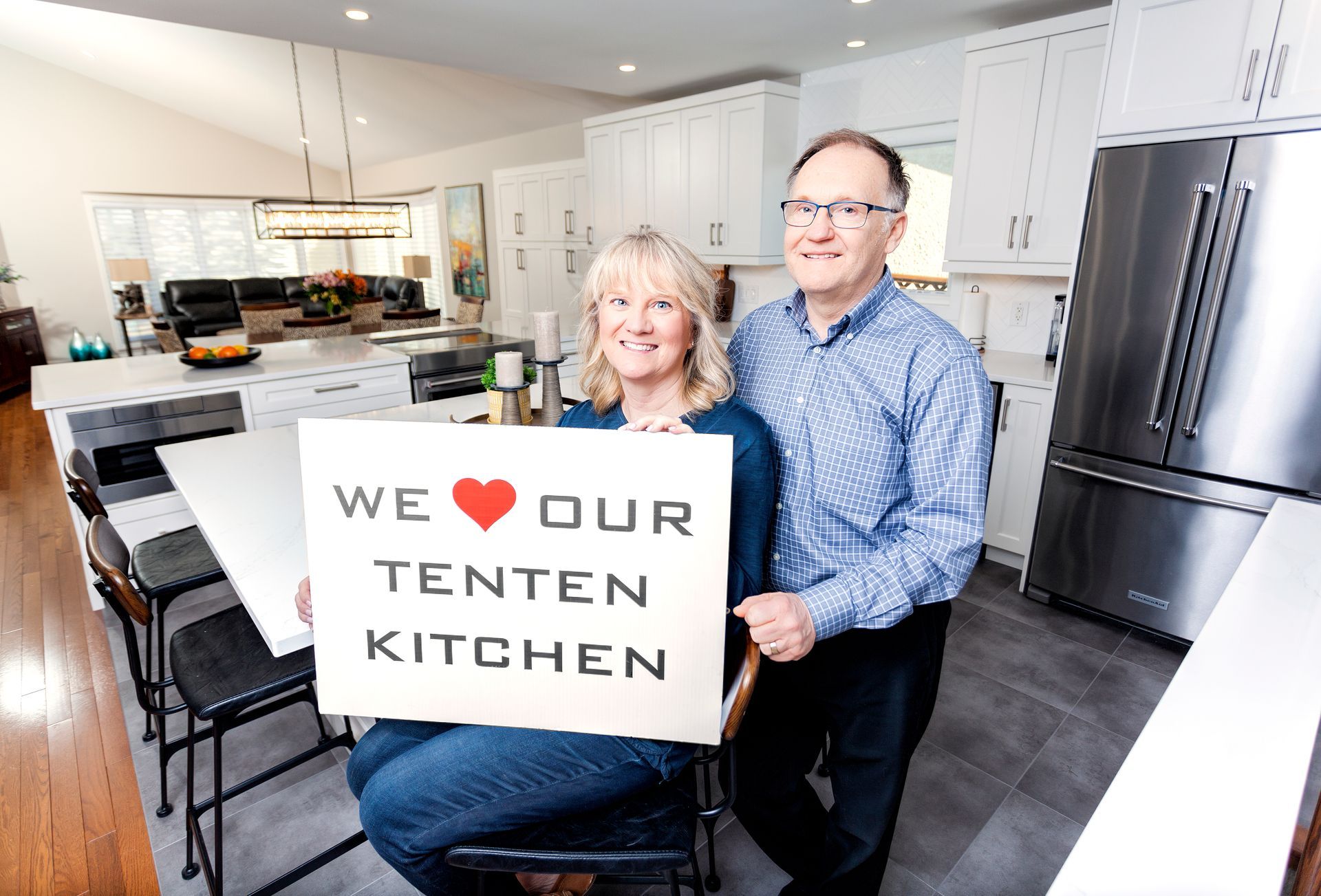 a man and woman are holding a sign that says we love our tenten kitchen .