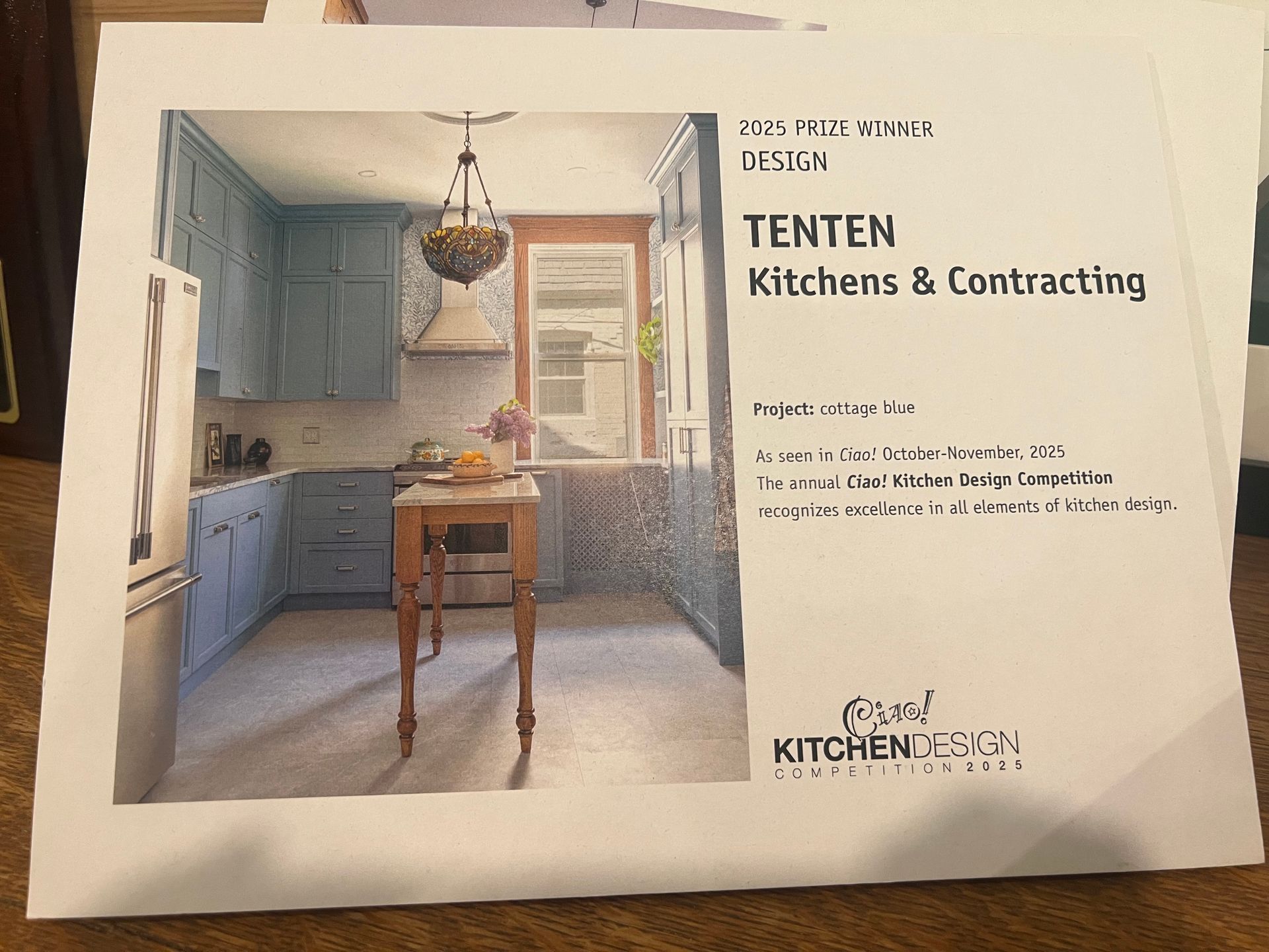 A flyer for Tenten Kitchens & Contracting featuring a photo of a blue kitchen with a wooden island and pendant lighting.