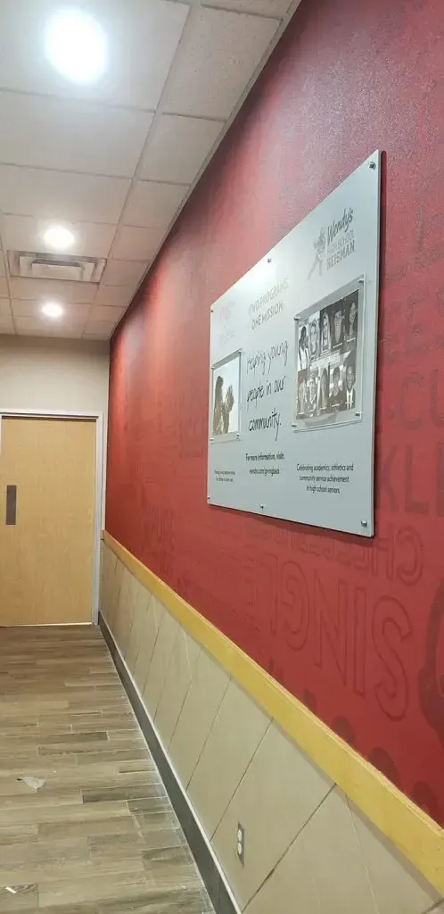 Empty hallway with red walls, beige floor, and a mounted wall display near a closed door.
