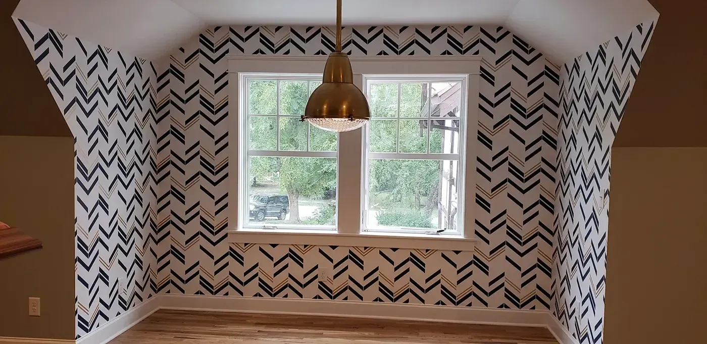 Empty dining nook with black-and-white patterned wallpaper, a window, and a hanging pendant light.