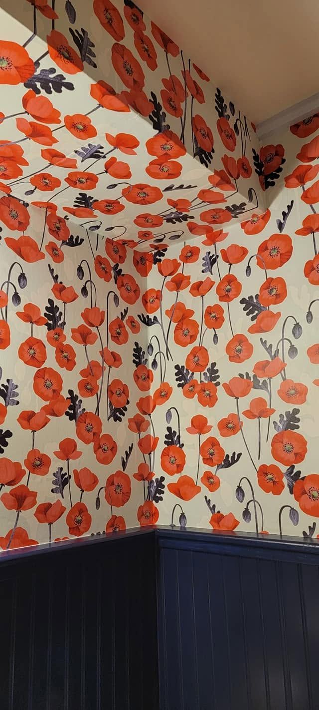 Corner of a room with orange floral wallpaper above dark blue wainscoting.