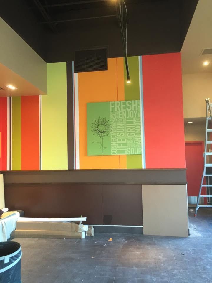 Colorful wall mural in an unfinished room with dark lower walls and exposed ceiling.