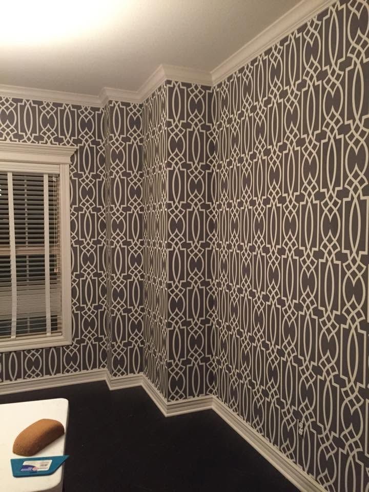 Patterned room with dark carpet, white trim, and a window with blinds above a bed edge.