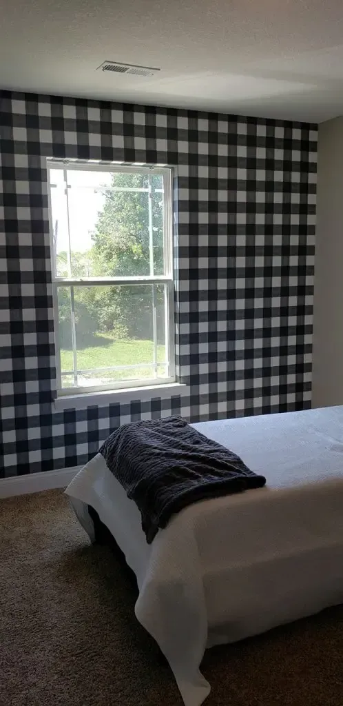 Bedroom with black-and-white checkered curtains, a window, and a bed with white bedding