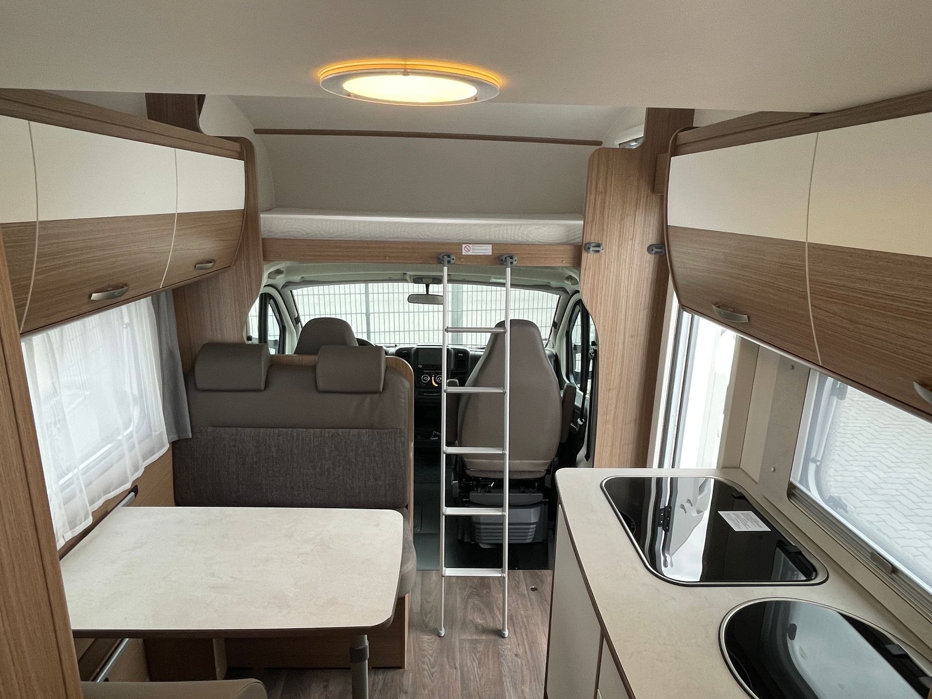 The inside of a camper van with a table and a ladder.