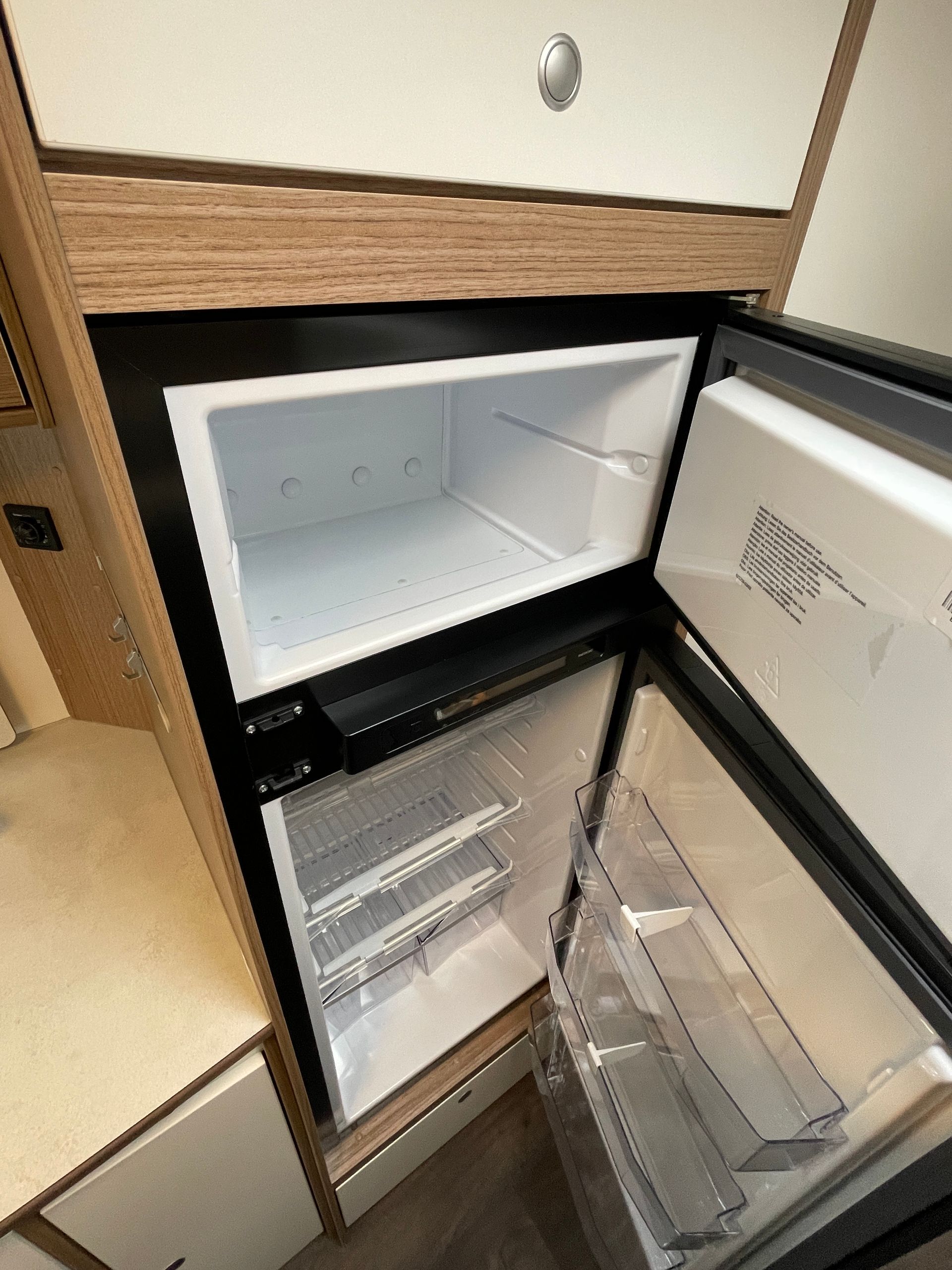An empty refrigerator with the door open in a kitchen.