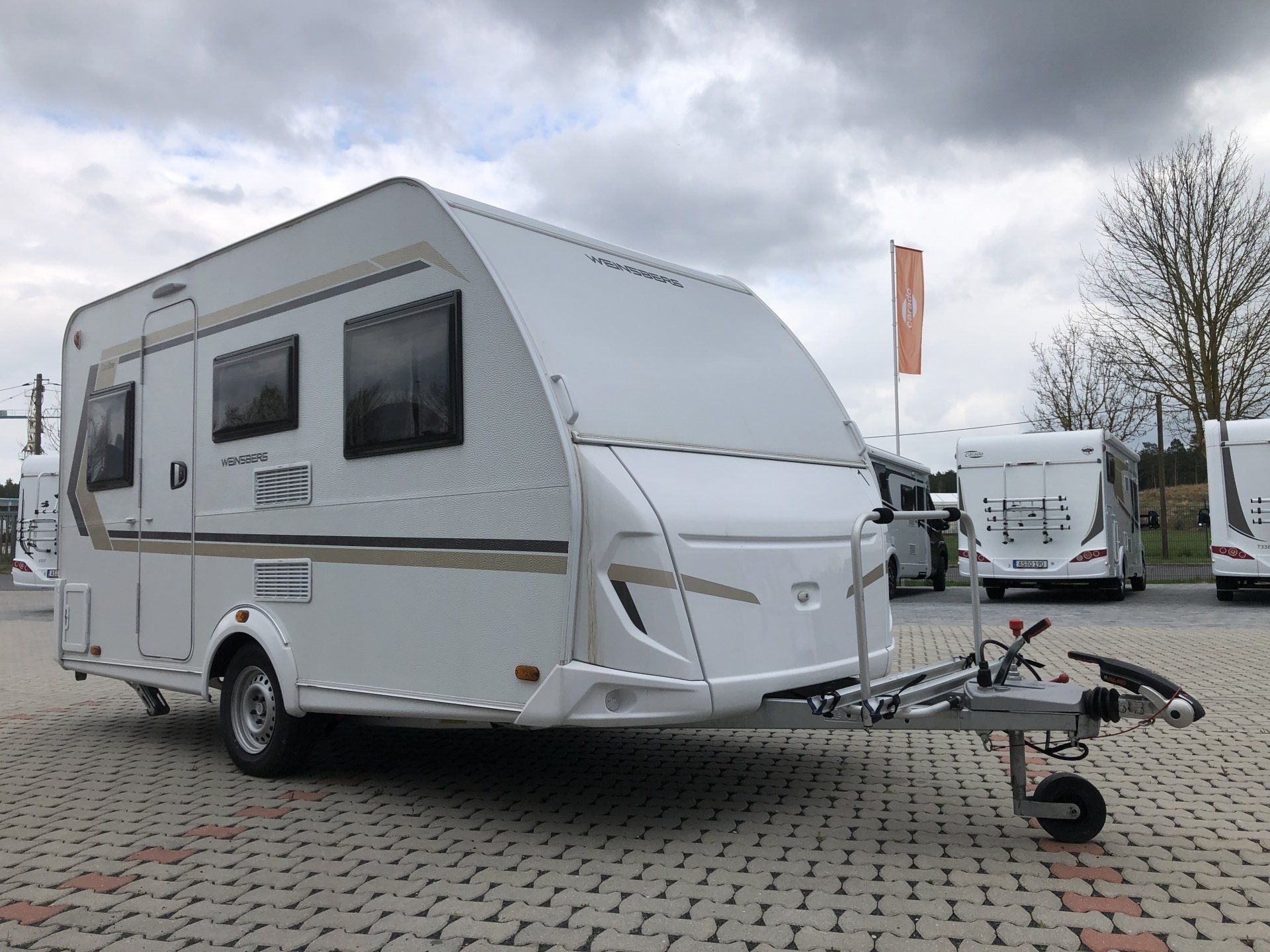 A white camper trailer is parked in a parking lot.