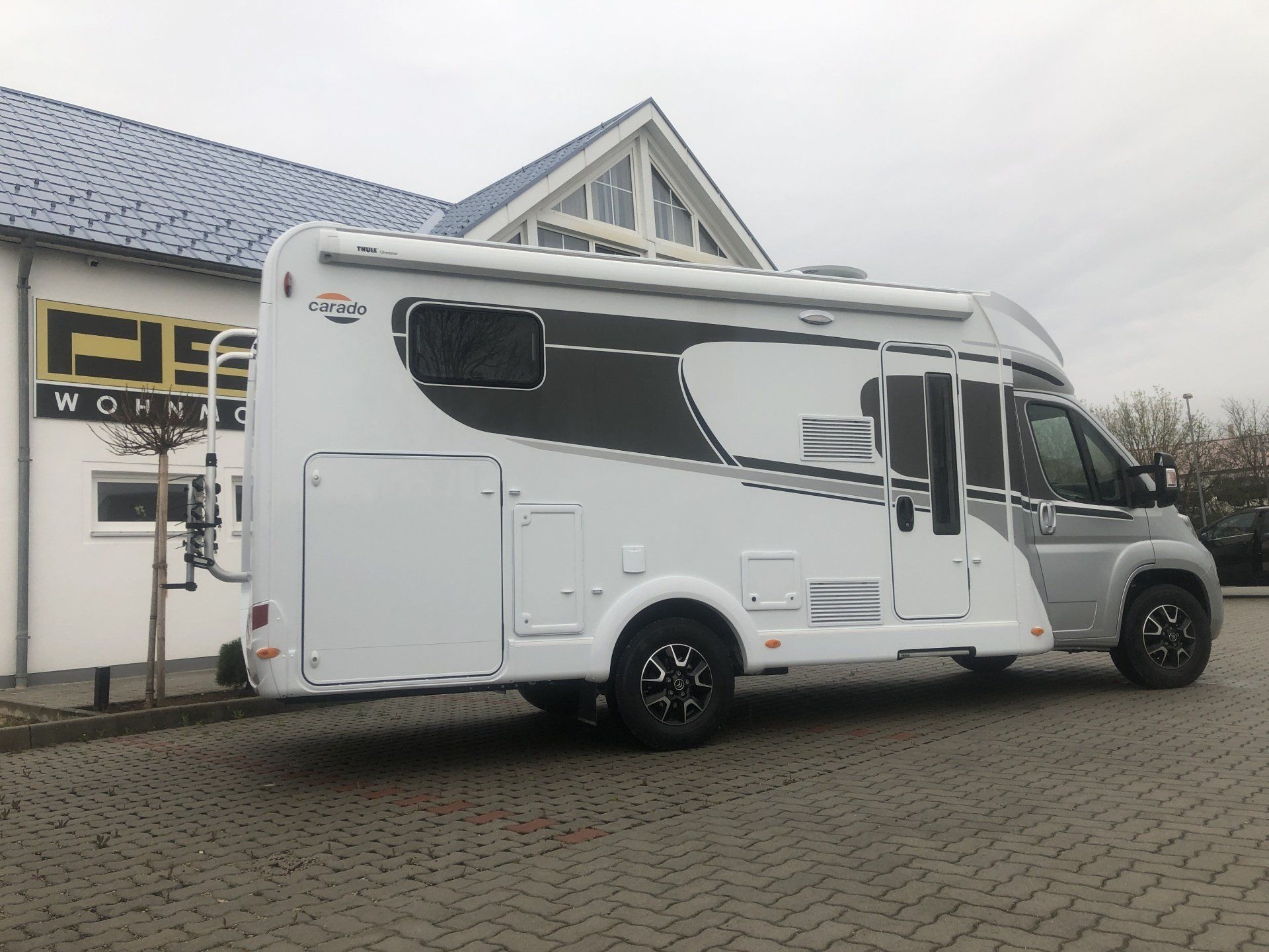 Ein weißes Wohnmobil ist vor einem Gebäude geparkt.