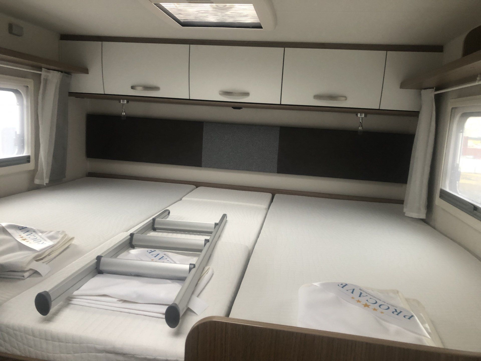 In einem Wohnmobil steht eine Leiter auf einem Bett.