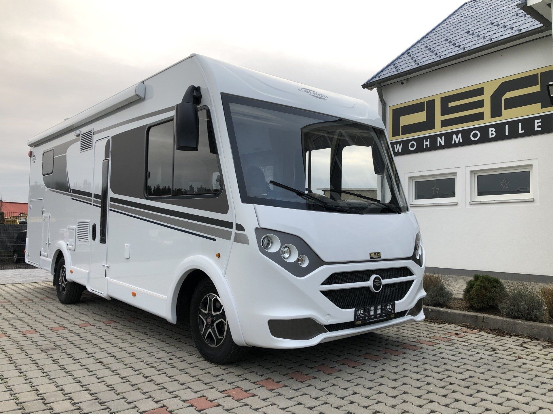 Ein weißes Wohnmobil ist vor einem Gebäude geparkt.