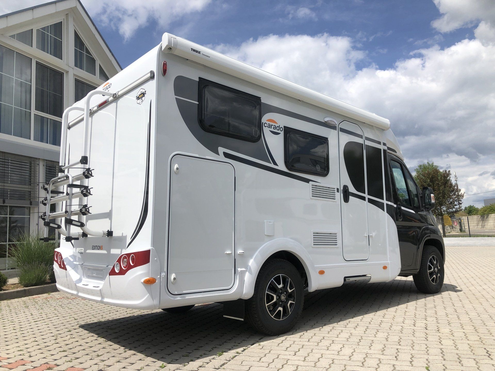 Ein weiß-schwarzes Wohnmobil ist vor einem Gebäude geparkt.