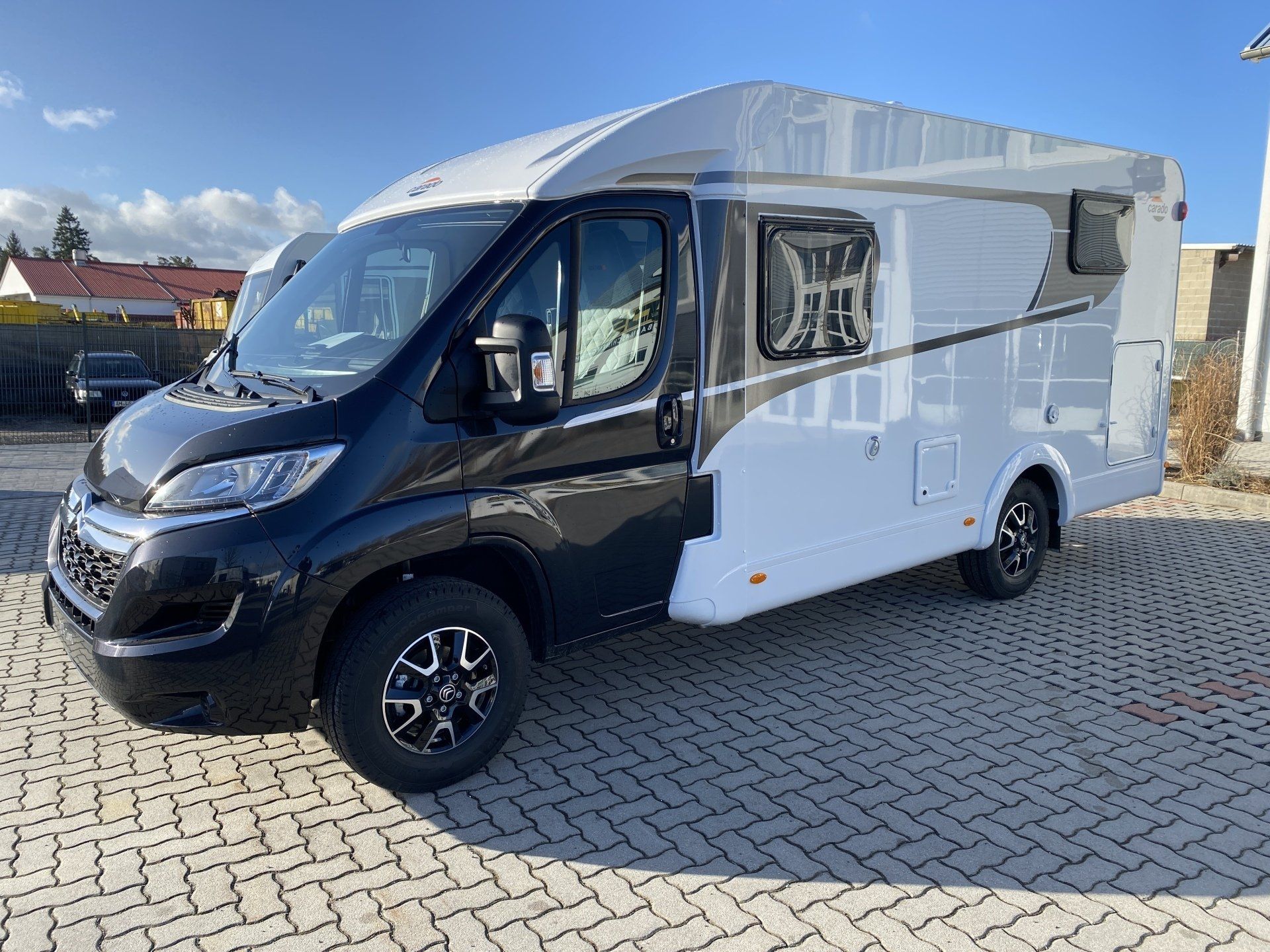 Ein schwarz-weißes Wohnmobil steht auf einer gepflasterten Auffahrt.