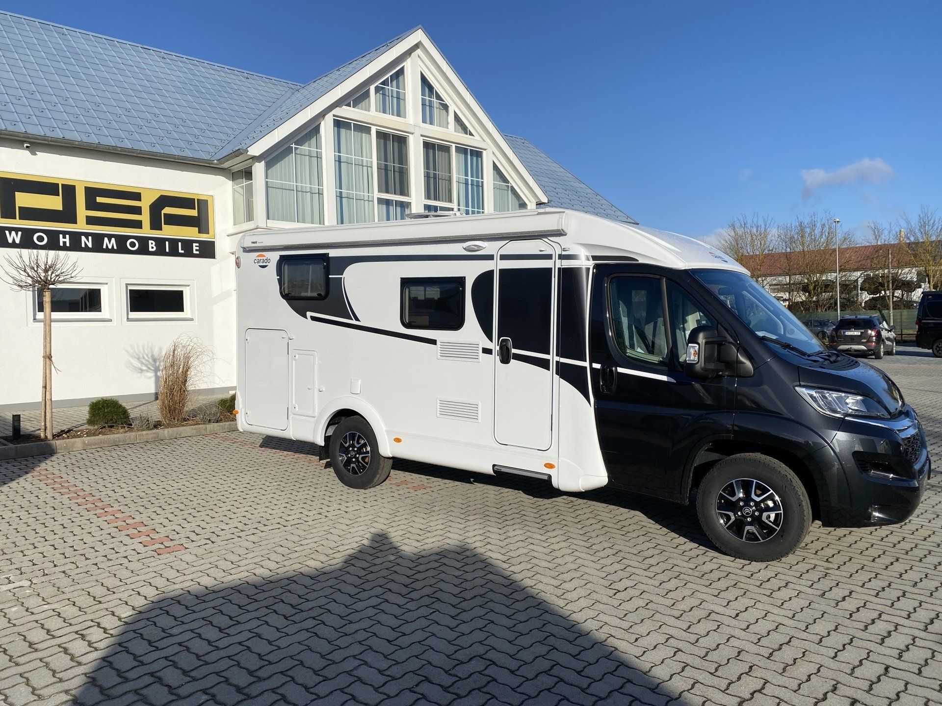 Ein schwarz-weißes Wohnmobil ist vor einem Gebäude geparkt.