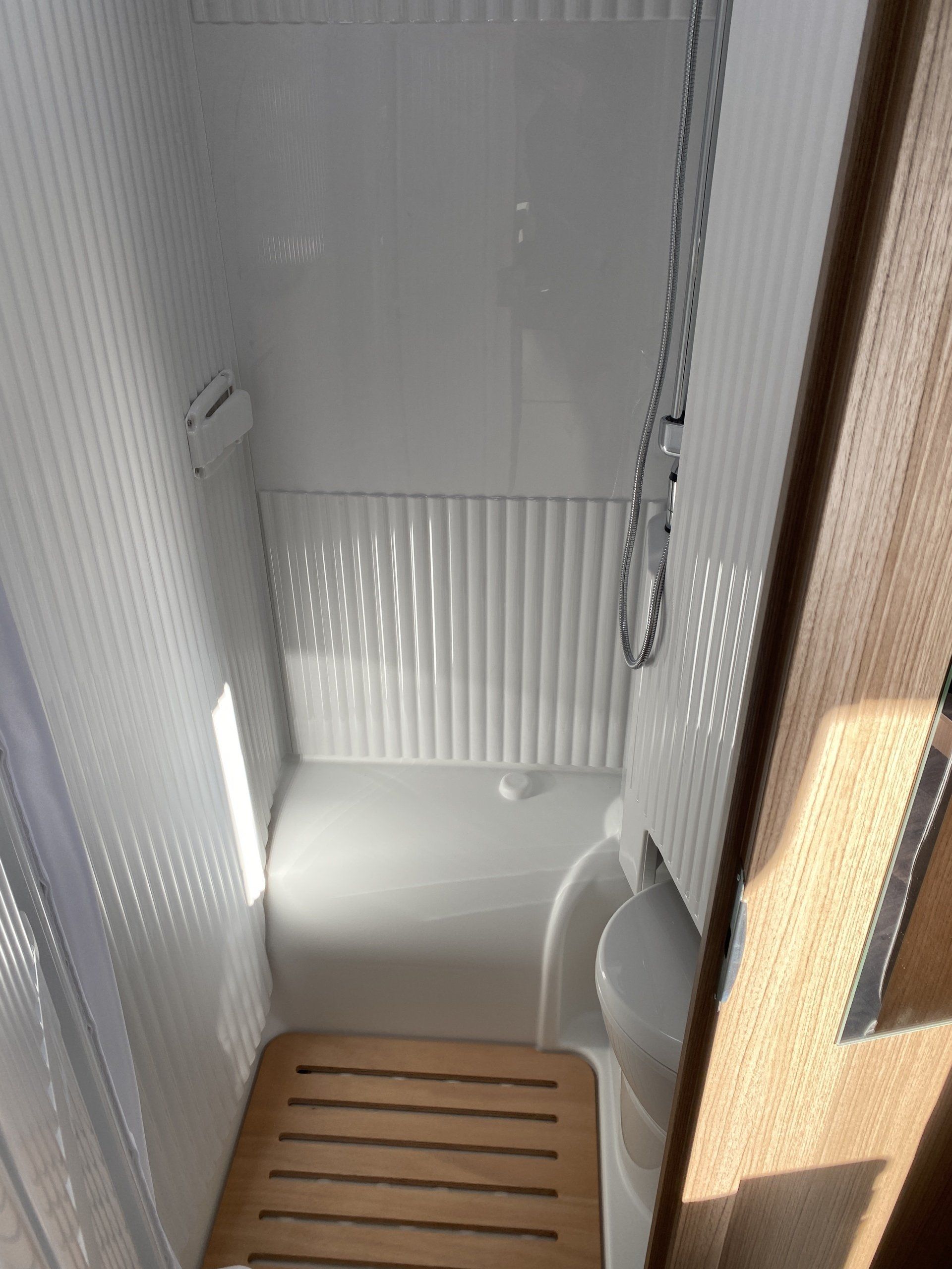 Ein Badezimmer mit Dusche, Toilette und Holzboden.
