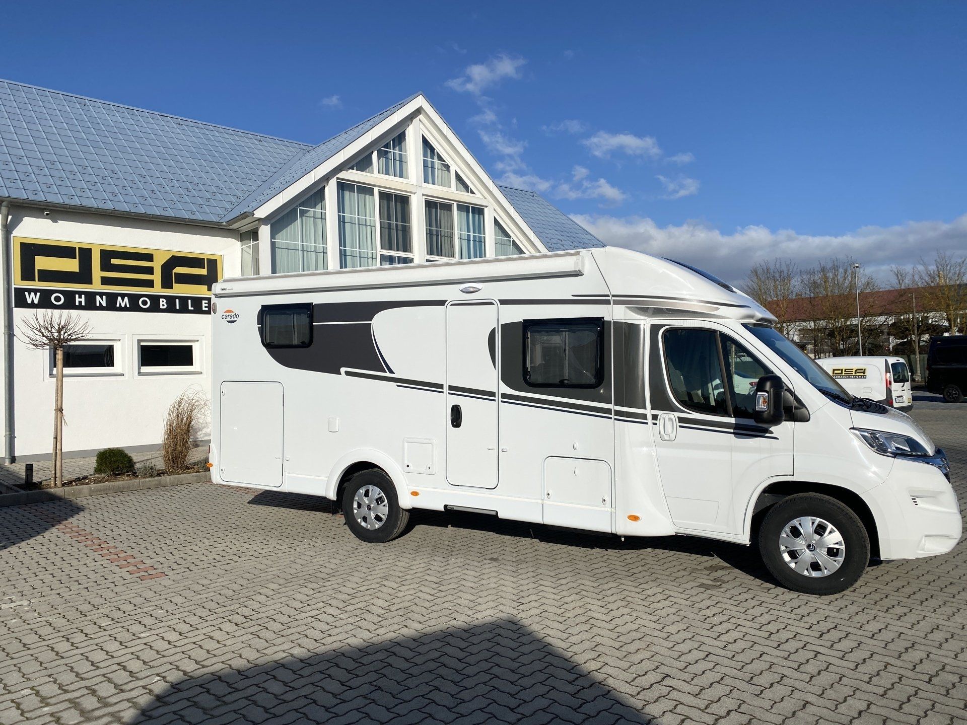 Ein weißes Wohnmobil ist vor einem Gebäude geparkt.