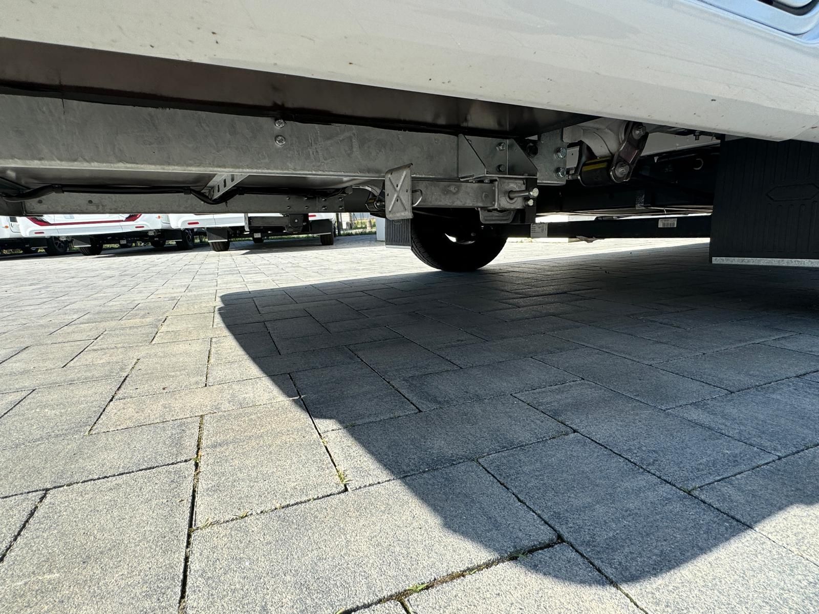 Auf einer gepflasterten Auffahrt ist ein Auto mit einem daran befestigten Anhänger geparkt.