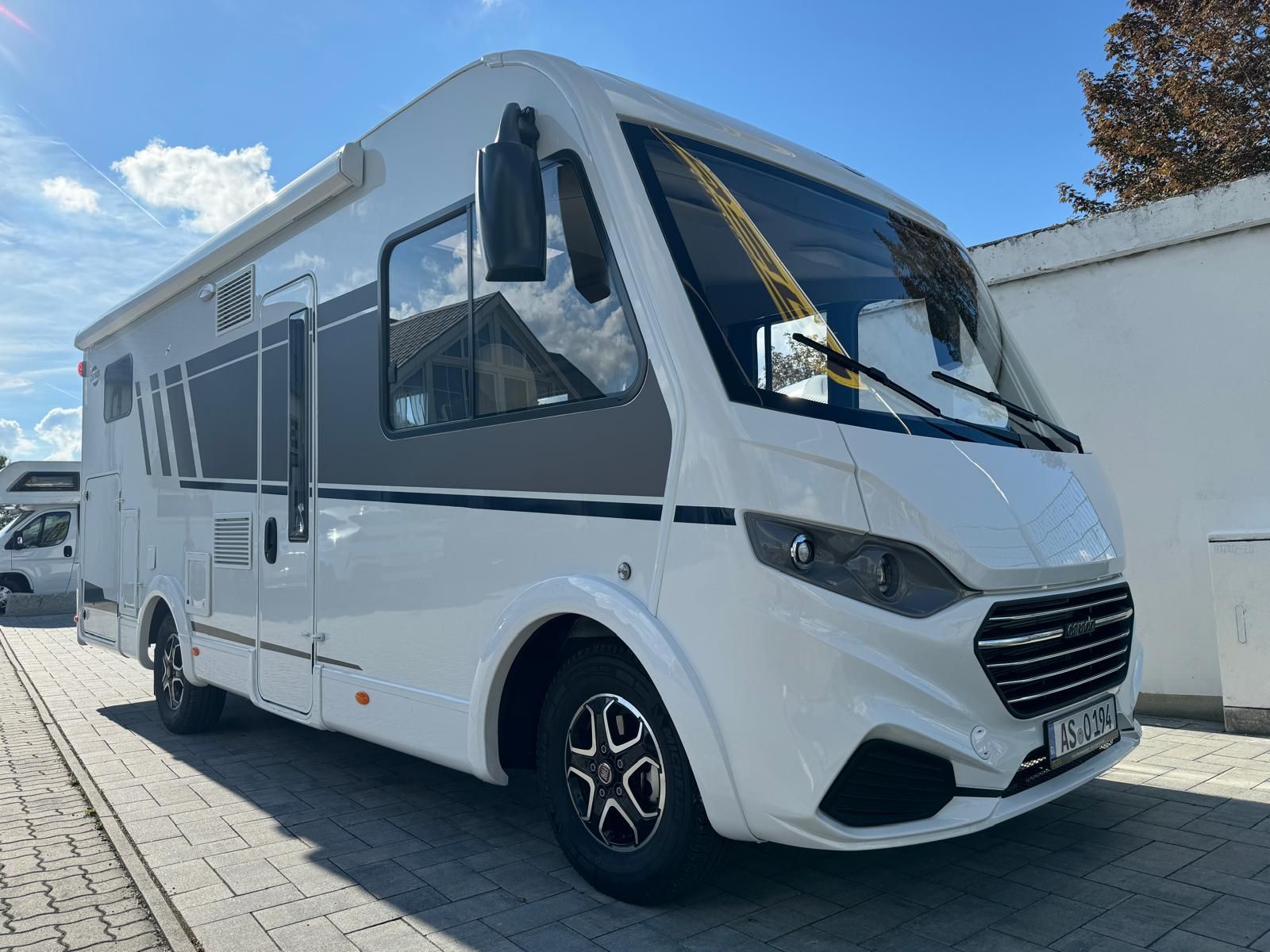 Ein weißes Wohnmobil steht auf einem Parkplatz.