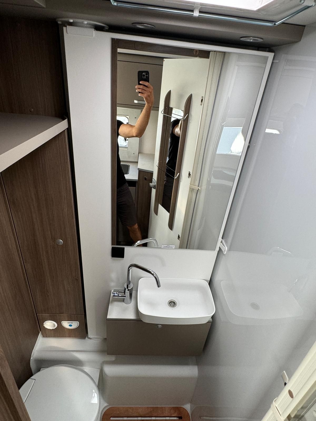 Eine Person macht ein Foto von ihrem Spiegelbild in einem Badezimmerspiegel.