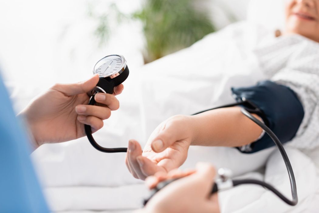 In una luminosa clinica, la pressione sanguigna viene misurata sul braccio di una persona con un bracciale e un manometro.