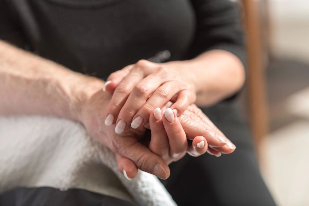 Due mani che si stringono delicatamente in primo piano, con uno sfondo morbido e sfocato.