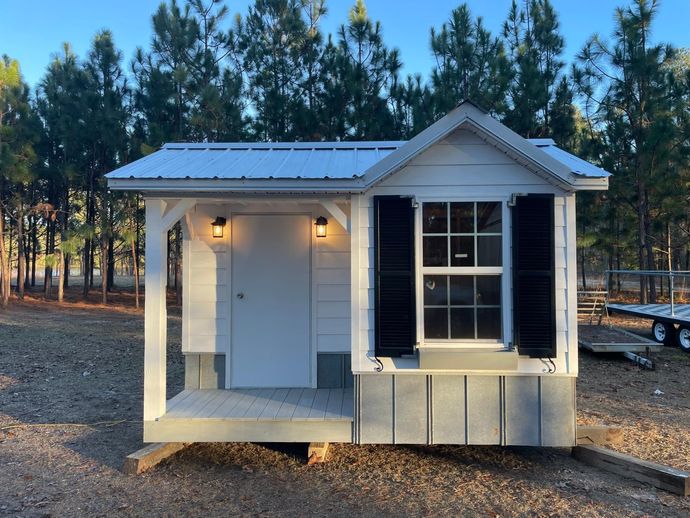A small white house with a porch and a window.