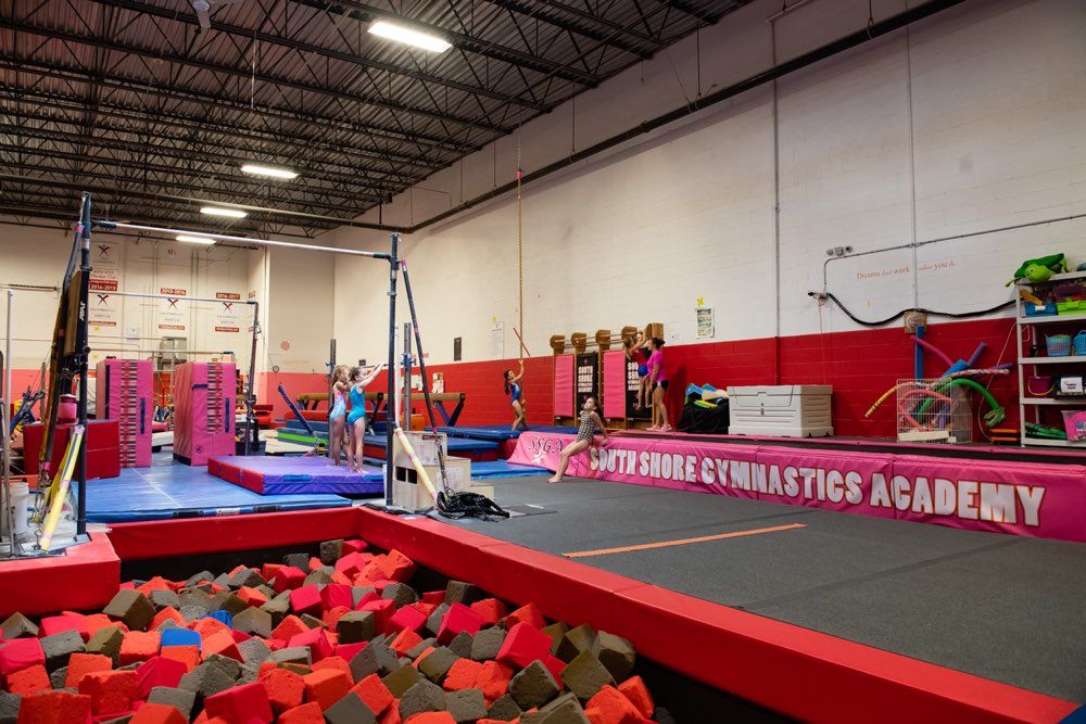 Gymnastics academy interior with various training apparatus, children practicing.