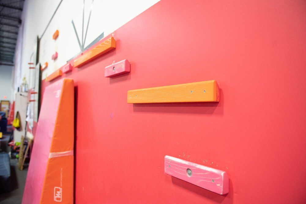 Red climbing wall with various colored handholds.