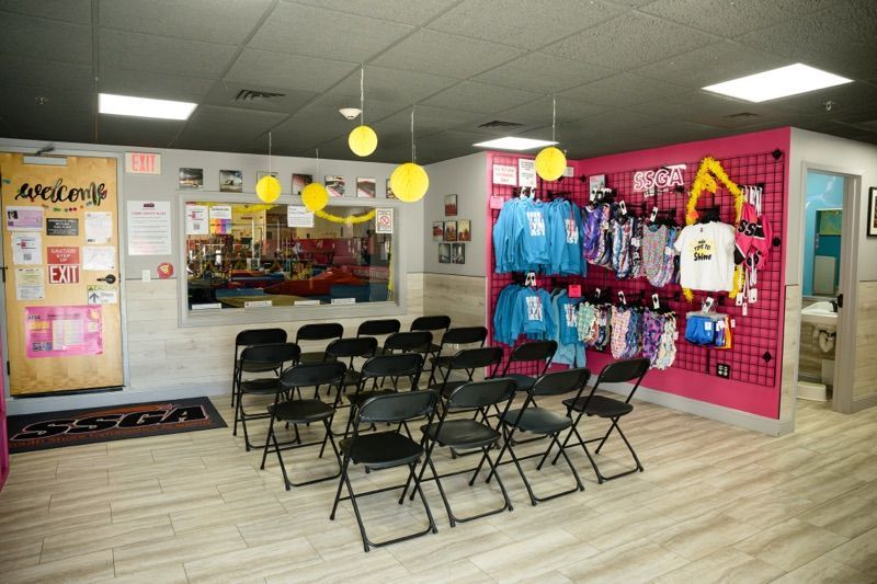 Interior room with rows of black chairs, merchandise on display, and a window.