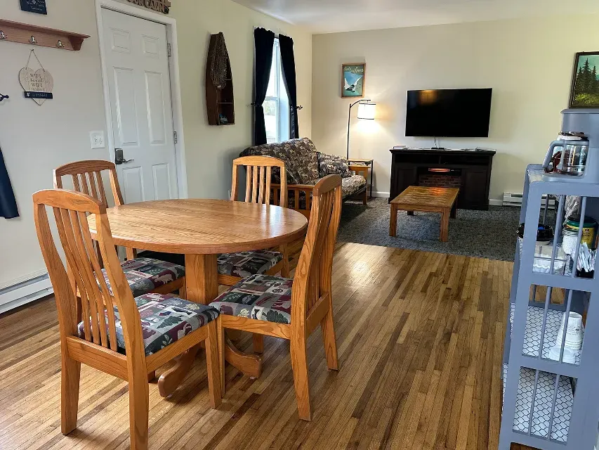 A living room with a table and chairs and a flat screen tv.