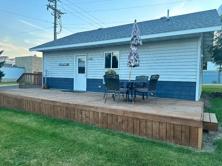 A small house with a wooden deck and a table and chairs on it.