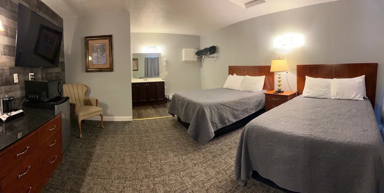 A hotel room with two beds and a television.