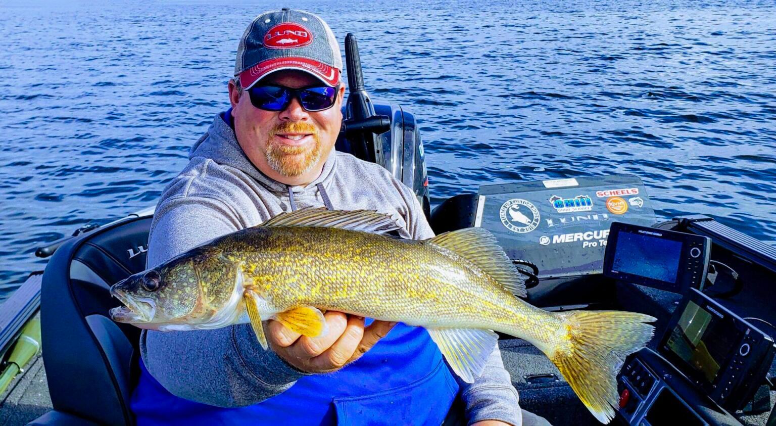 A man is sitting in a boat holding a large fish.
