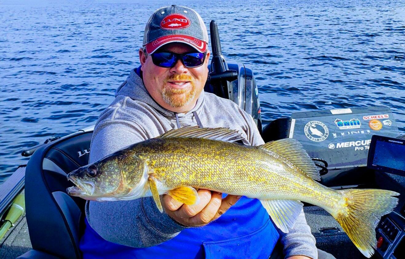 A man is sitting in a boat holding a large fish.
